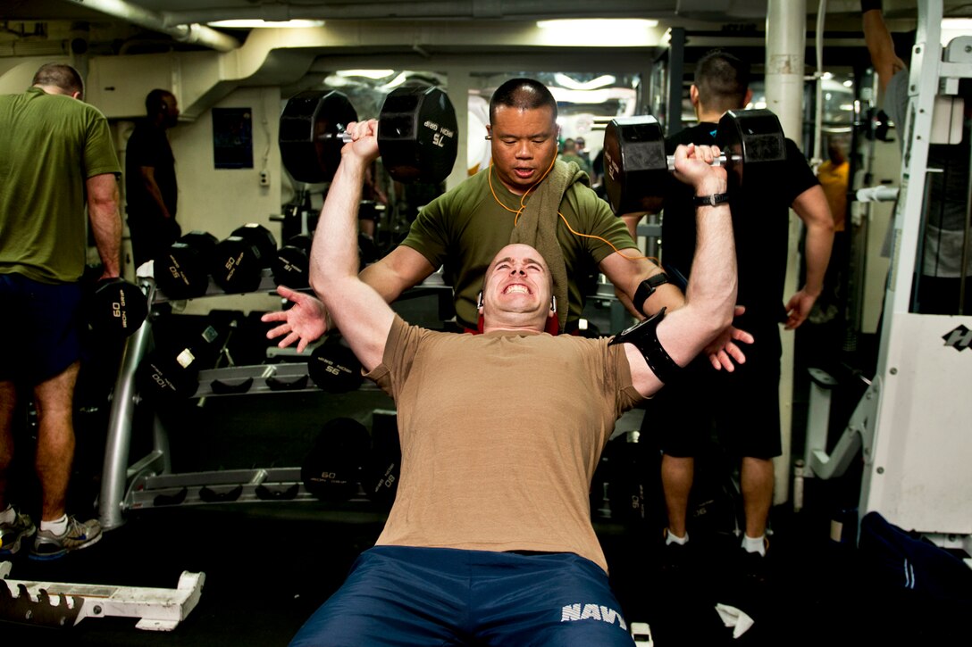 U.S. Navy Lt. Cmdr. Kevin Gue spots Lt. Todd Leroux during a weightlifting session aboard the USS John C. Stennis in the Arabian Sea, Jan. 8, 2012. The John C. Stennis is deployed to the U.S. 5th Fleet area of responsibility to conduct maritime security operations and support missions as part of Operation Enduring Freedom.  
