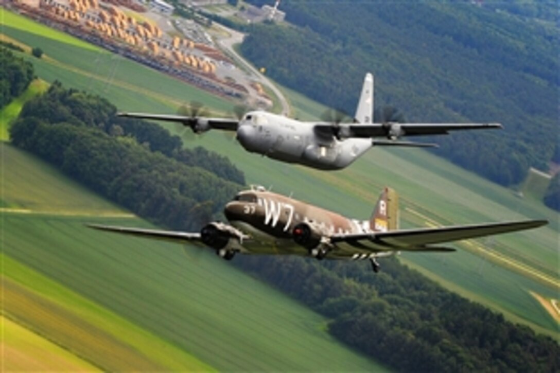 A Douglas C-47 Skytrain, known as Whiskey 7, flies alongside a C-130J Super Hercules from the 37th Airlift Squadron over Ramstein Air Base, Germany, May 30, 2014. The C-47 is participating in base activities with its legacy unit, the 37th Airlift Squadron, before returning to Normandy, France, to recreate its World War II role, dropping paratroopers over the original drop zone in Sainte-Mere Eglise, France.