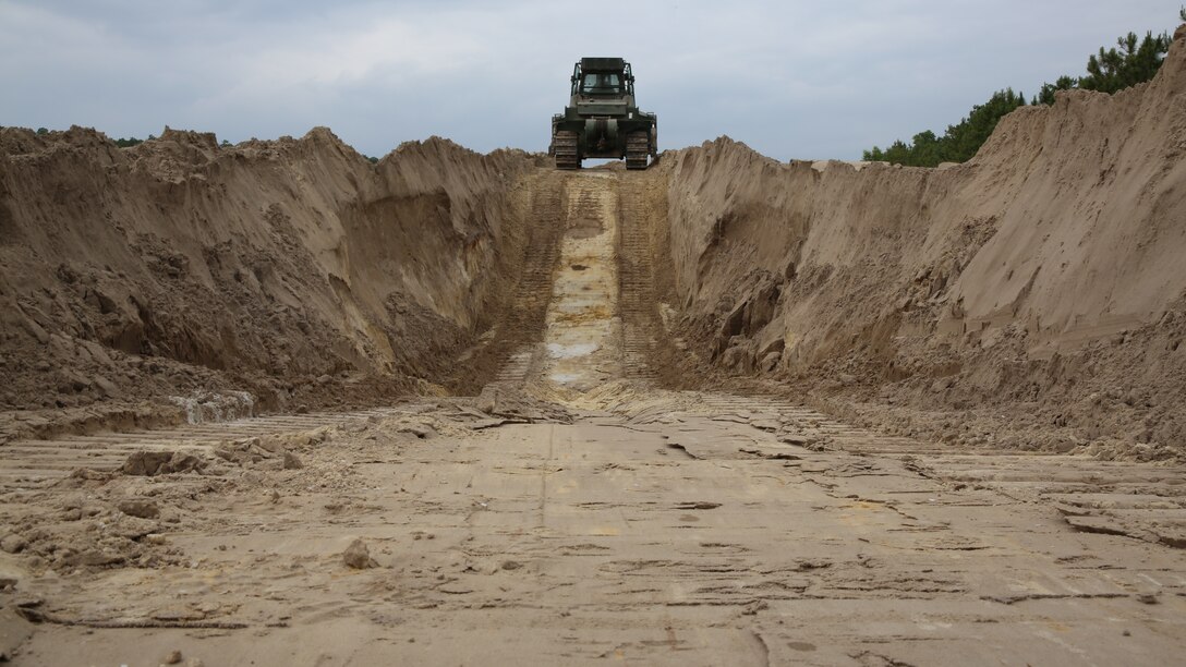 Heavy equipment operators, combat engineers and heavy equipment mechanics build a tank ditch using a MCT 850J Bulldozer, during a company field exercise at Marine Corps Base Camp Lejeune, N.C., May 30, 2014. A tank ditch is a protective measure used to prevent tanks from being seen when firing. The company exercise is a tool used to prepare the company for an upcoming squadron field training exercise.