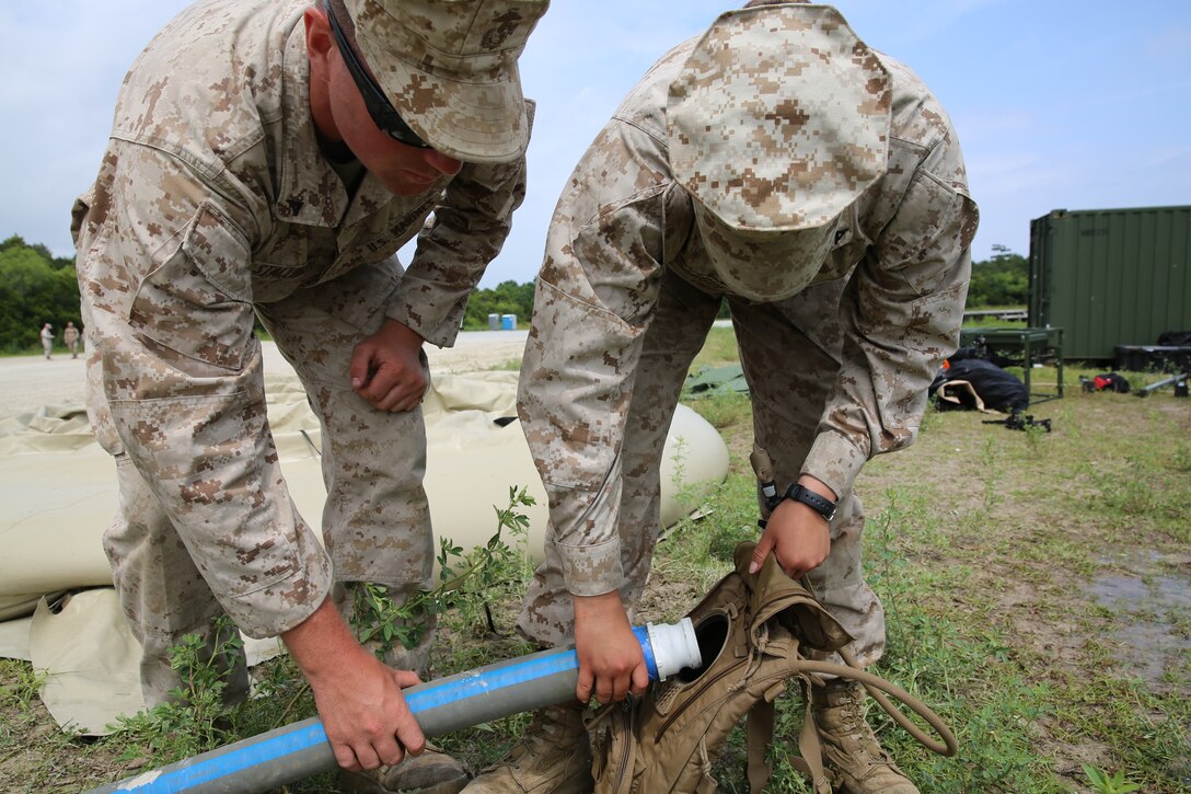 Lance Cpl. Quentin J. Stallings (left) helps Lance Cpl. Alyse S. Rodriguez (right) fill up her CamelBak with water purified by the Tactical Water Purification System, during a field exercise at Marine Corps Base Camp Lejeune, N.C., May 30, 2014. The Marines used the light weight water purifying system to purify seawater to support Marines in the squadron with water to stay hydrated, hygiene properly and cook. Stallings is a water support technician with MWSS-271. Rodriguez is a field radio operator with the squadron. 