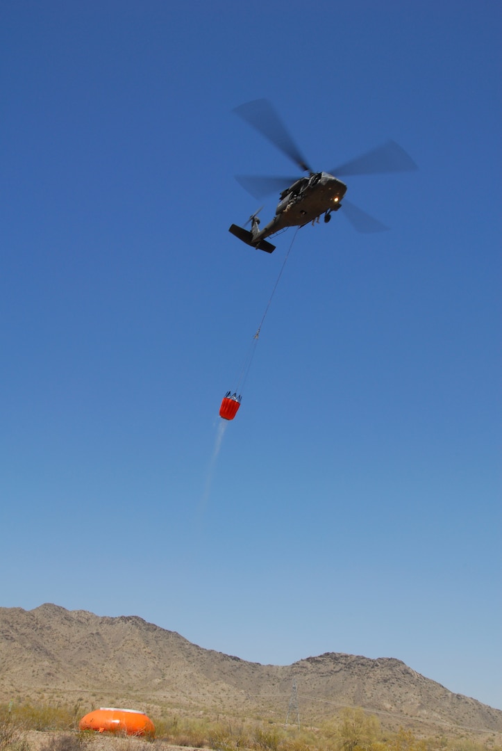Soldiers from the Arizona Army National Guard's Company A, 2nd Battalion, 285th Aviation Regiment use a UH-60 Black Hawk helicopter to draw and drop water through the use of a buoy wall and a Bambi Bucket during wildfire firefighting training at the Buckeye Armed Forces Reserve Center, Ariz. The training is designed for aviators from the Arizona Army Guard to receive validation by the Arizona State Forestry Division in order to provide aviation support to state wildfire emergencies. (U.S. Army photo by Sgt. Lauren DeVita)