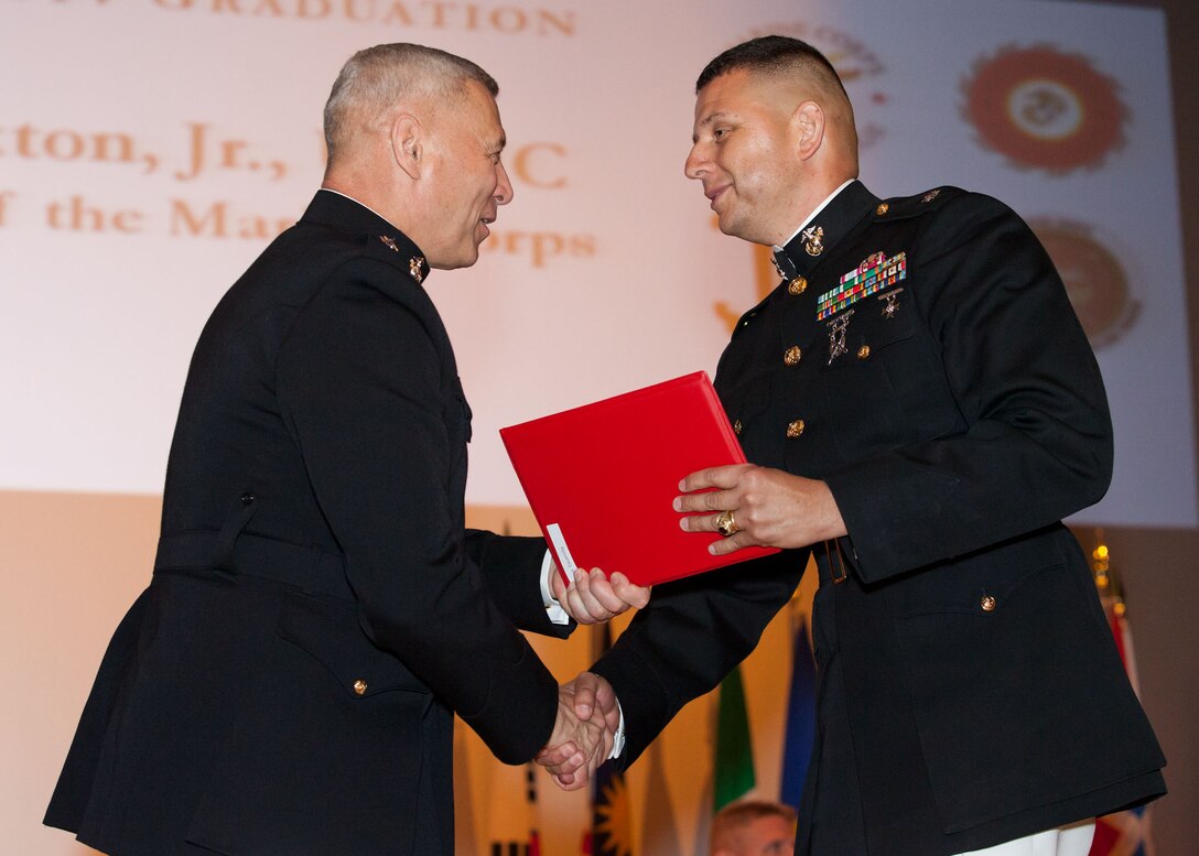The Assistant Commandant of the Marine Corps, Gen. John M. Paxton, Jr., left, hands a diploma to a student who graduated from the Marine Corps University for the academic year of 2013-2014 at U.S. Marine Corps Base Quantico, Va., June 4, 2014. (U.S. Marine Corps by Cpl. Tia Dufour/Released)