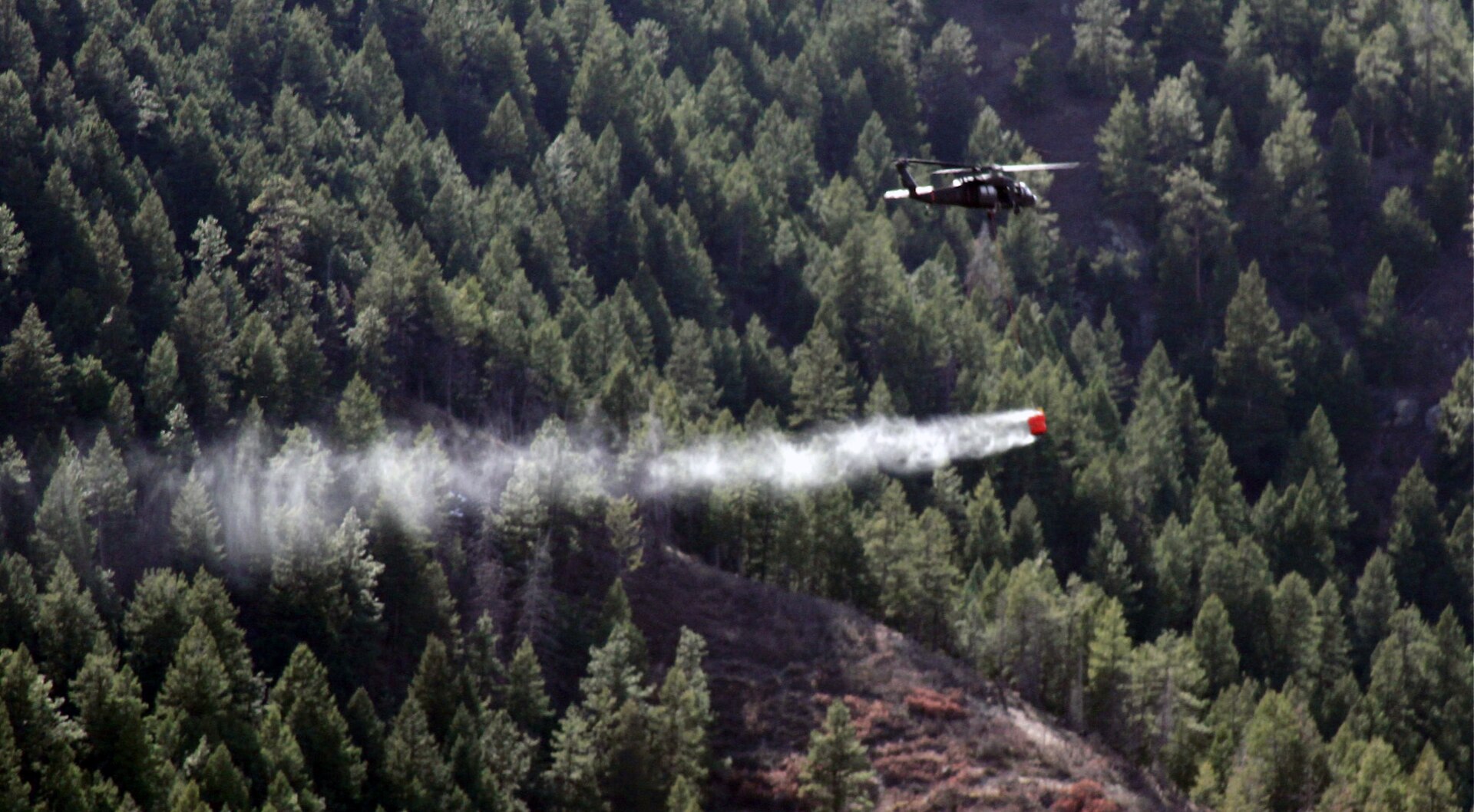 A UH-60 Black Hawk helicopter from the Colorado Army National Guard's 2nd Battalion, 135th General Support Aviation, drops 500 gallons of water from a specialized bucket onto the Lower North Fork Fire in the vicinity of Conifer Colo., March 28, 2012.