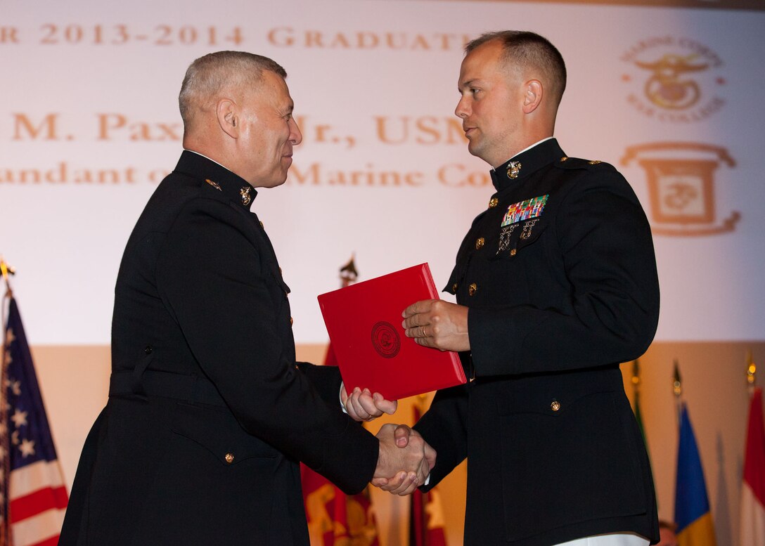 The Assistant Commandant of the Marine Corps, Gen. John M. Paxton, Jr., left, hands a diploma to a student who graduated from the Marine Corps University for the academic year of 2013-2014 at U.S. Marine Corps Base Quantico, Va., June 4, 2014. (U.S. Marine Corps by Cpl. Tia Dufour/Released)