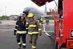 Two Estonian firefighters converse during a drill at Amari Air Base, Estonia, in front of a KC-135 Stratotanker operated by the 171st Air Refueling Squadron, 127th Wing, Michigan Air National Guard, June 11, 2012. Michigan Airmen deployed to Estonia in mid June 2012 in support of the Saber Strike Exercise, a multinational exercise based in Latvia and Estonia.