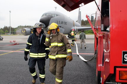 Two Estonian firefighters converse during a drill at Amari Air Base, Estonia, in front of a KC-135 Stratotanker operated by the 171st Air Refueling Squadron, 127th Wing, Michigan Air National Guard, June 11, 2012. Michigan Airmen deployed to Estonia in mid June 2012 in support of the Saber Strike Exercise, a multinational exercise based in Latvia and Estonia.