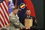 Gen. David G. Perkins, commanding general of U.S. Training and Doctrine Command (TRADOC), left, presents a plaque to Sgt. 1st Class Paul Deegan, of the 164th Regiment Regional Training Institute, upon naming Deegan the 2013 TRADOC National Guard Instructor of the Year during a ceremony May 30, 2014, in Fort Eustis, Virginia. 