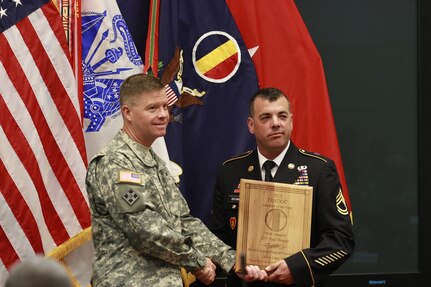 Gen. David G. Perkins, commanding general of U.S. Training and Doctrine Command (TRADOC), left, presents a plaque to Sgt. 1st Class Paul Deegan, of the 164th Regiment Regional Training Institute, upon naming Deegan the 2013 TRADOC National Guard Instructor of the Year during a ceremony May 30, 2014, in Fort Eustis, Virginia. 