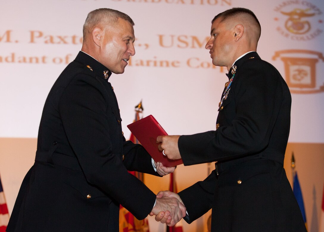 The Assistant Commandant of the Marine Corps, Gen. John M. Paxton, Jr., left, hands a diploma to a student who graduated from the Marine Corps University for the academic year of 2013-2014 at U.S. Marine Corps Base Quantico, Va., June 4, 2014. (U.S. Marine Corps by Cpl. Tia Dufour/Released)