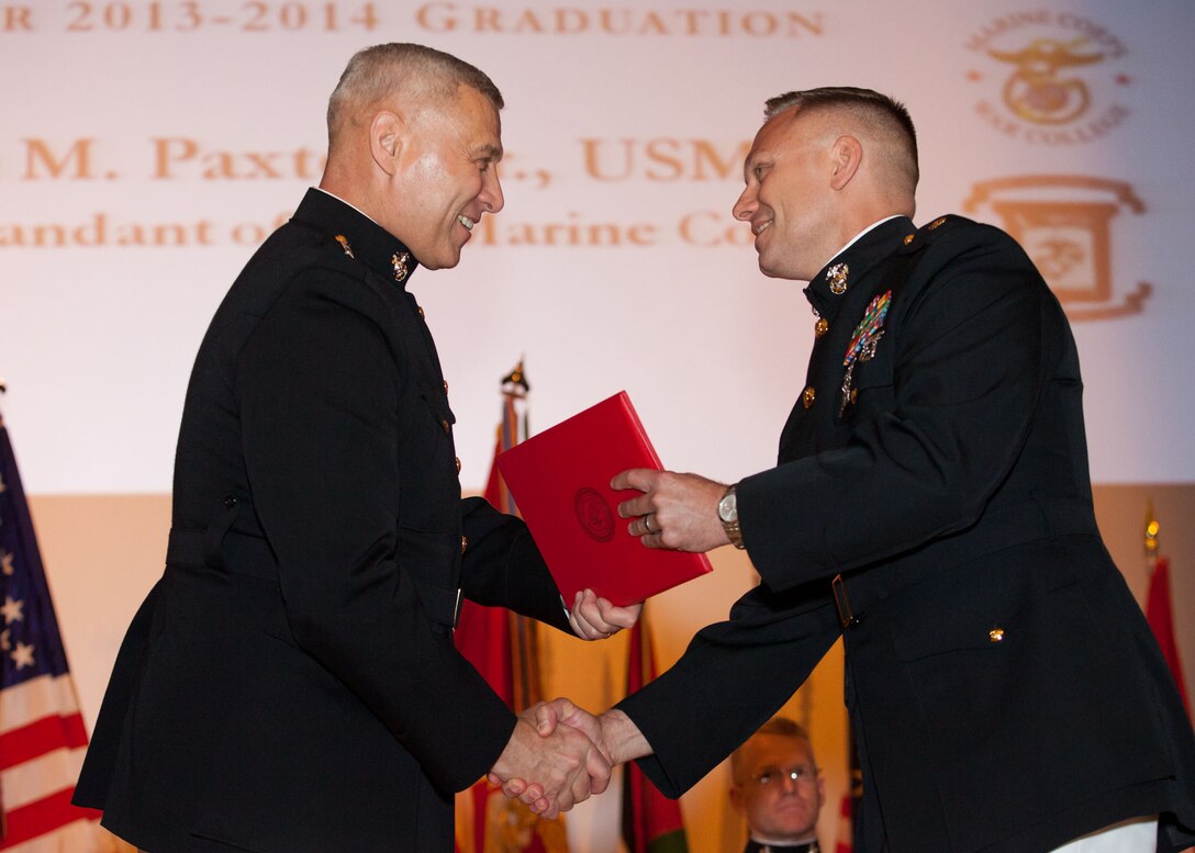 The Assistant Commandant of the Marine Corps, Gen. John M. Paxton, Jr., left, hands a diploma to a student who graduated from the Marine Corps University for the academic year of 2013-2014 at U.S. Marine Corps Base Quantico, Va., June 4, 2014. (U.S. Marine Corps by Cpl. Tia Dufour/Released)
