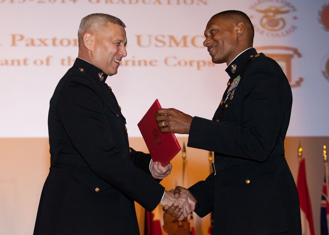 The Assistant Commandant of the Marine Corps, Gen. John M. Paxton, Jr., left, hands a diploma to a student who graduated from the Marine Corps University for the academic year of 2013-2014 at U.S. Marine Corps Base Quantico, Va., June 4, 2014. (U.S. Marine Corps by Cpl. Tia Dufour/Released)