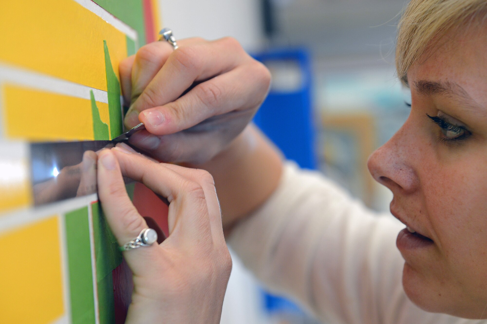 Senior Airman Danielle Snyder, 62nd Operations Support Squadron aircrew flight equipment journeyman, applies the finishing touches to a mural of the 62nd OSS patch May 18, 2014 at Joint Base Lewis-McChord, Wash. Snyder volunteered more than seven days of her off-duty time to complete the 4 feet by 3 feet mural. (U.S. Air Force photo/Airman 1st Class Jacob Jimenez)