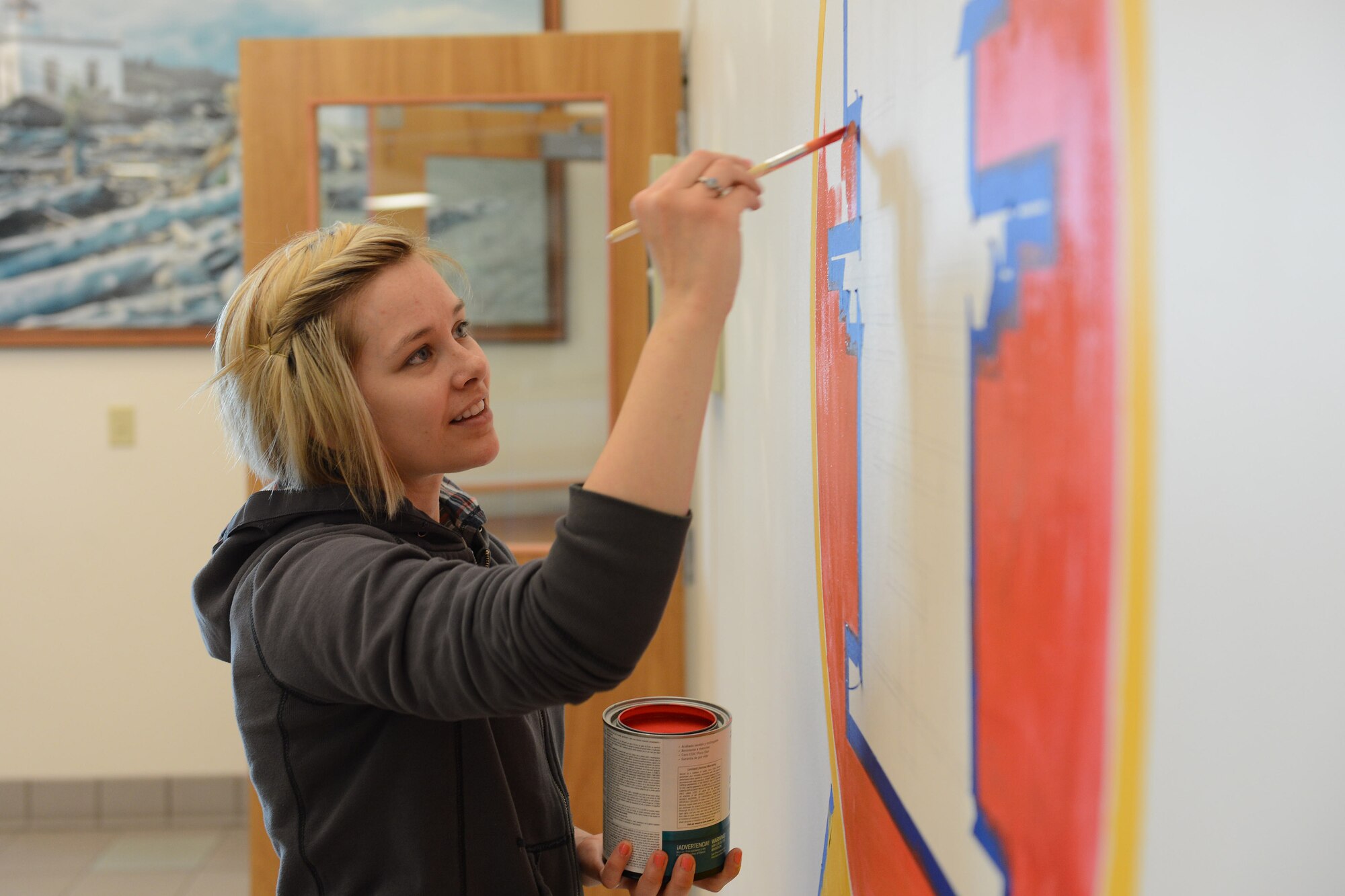 Senior Airman Danielle Snyder, 62nd Operations Support Squadron aircrew flight equipment journeyman, paints the outline of the 62nd OSS patch April 20, 2014 at Joint Base Lewis-McChord, Wash. Snyder spent more than 40 hours painting the mural for her squadron. (U.S. Air Force photo/Airman 1st Class Jacob Jimenez) 