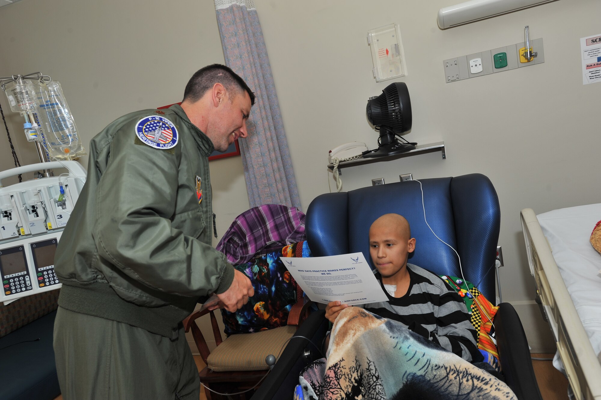 Maj. Mark Whisler, U.S. Air Force Viper West Heritage Flight team F-16 Fighting Falcon pilot, hands a poster to Jesus “Pee-Wee” Granados at the Sacred Heart Medical Hospital in Spokane, Wash., May 29, 2014.  The team visited the children to bring wishes and SkyFest memorabilia to those who couldn’t attend the event.  (U.S. Air Force photo by Staff Sgt. Veronica Montes/Released)