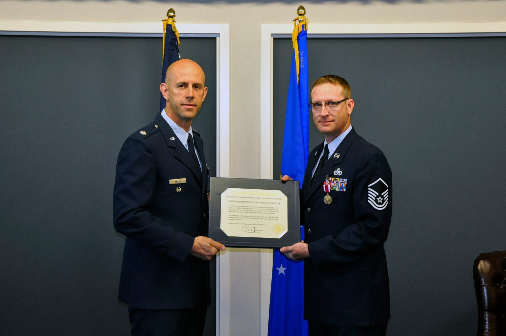 Lt. Col. John Knack (left), 62nd Maintenance Group deputy commander, delivers a certificate of retirement to Master Sgt. Dennis Kauffman (right), 62nd Maintenance Squadron engineering and logistics liaison, during his retirement ceremony May 30, 2014, at Joint Base Lewis-McChord, Wash. Kauffman led the 62nd MXS product improvement section for the last three years and retired after 22 of service to the United States Air Force. (U.S. Air Force photo/Master Sgt. Jared Pieschke) 