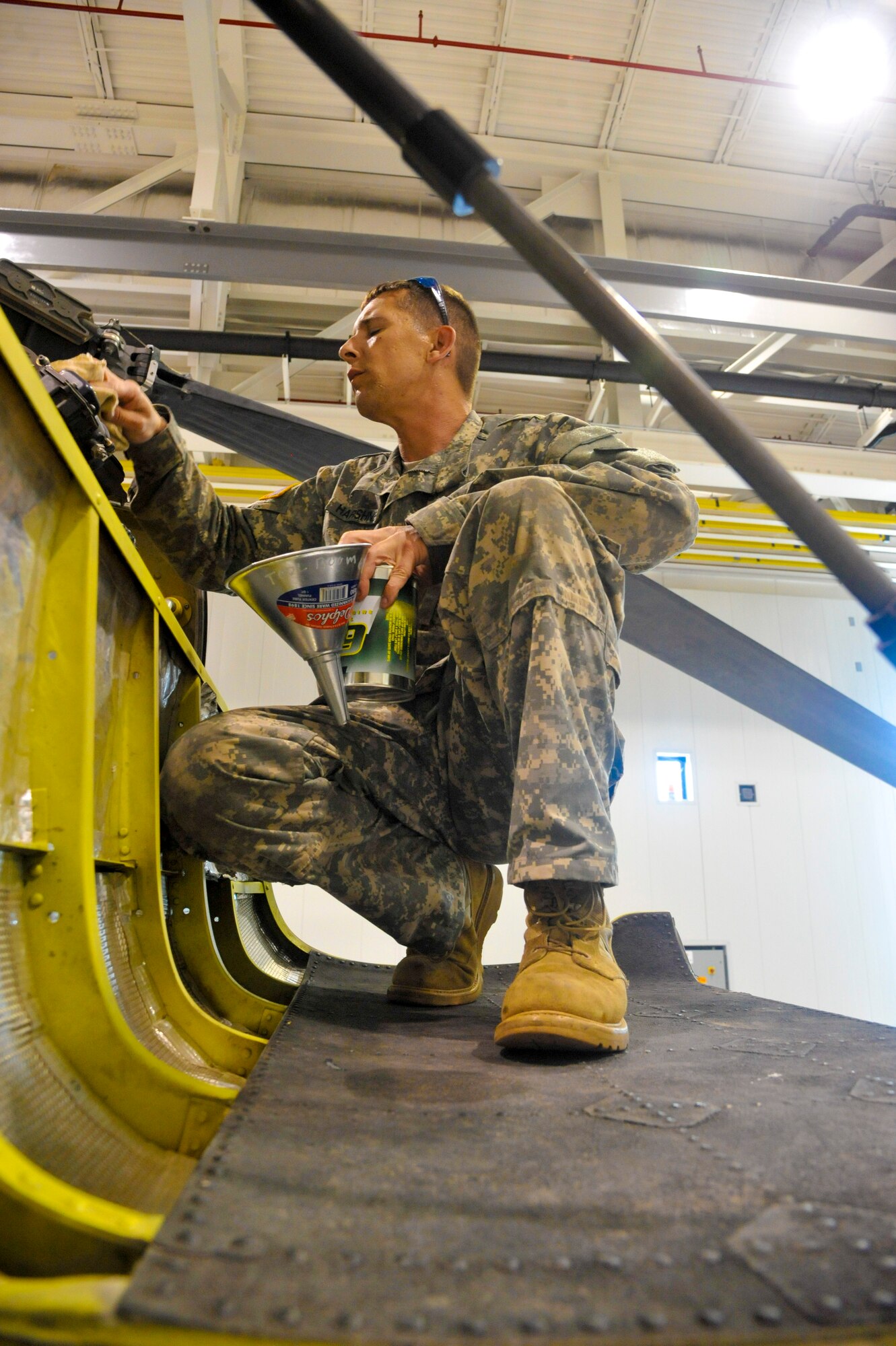 U.S. Army Sgt. Jeremy Harshner, 1-135th Attack Reconnaissance Battalion delta company avionics electronic armament specialist, fills an AH-64 Apache engine with oil at Whiteman Air Force Base, Mo., May 14, 2014. This is done to ensure the aircraft is prepared for flight. (U.S. Air Force photo by Airman 1st Class Keenan Berry/Released)