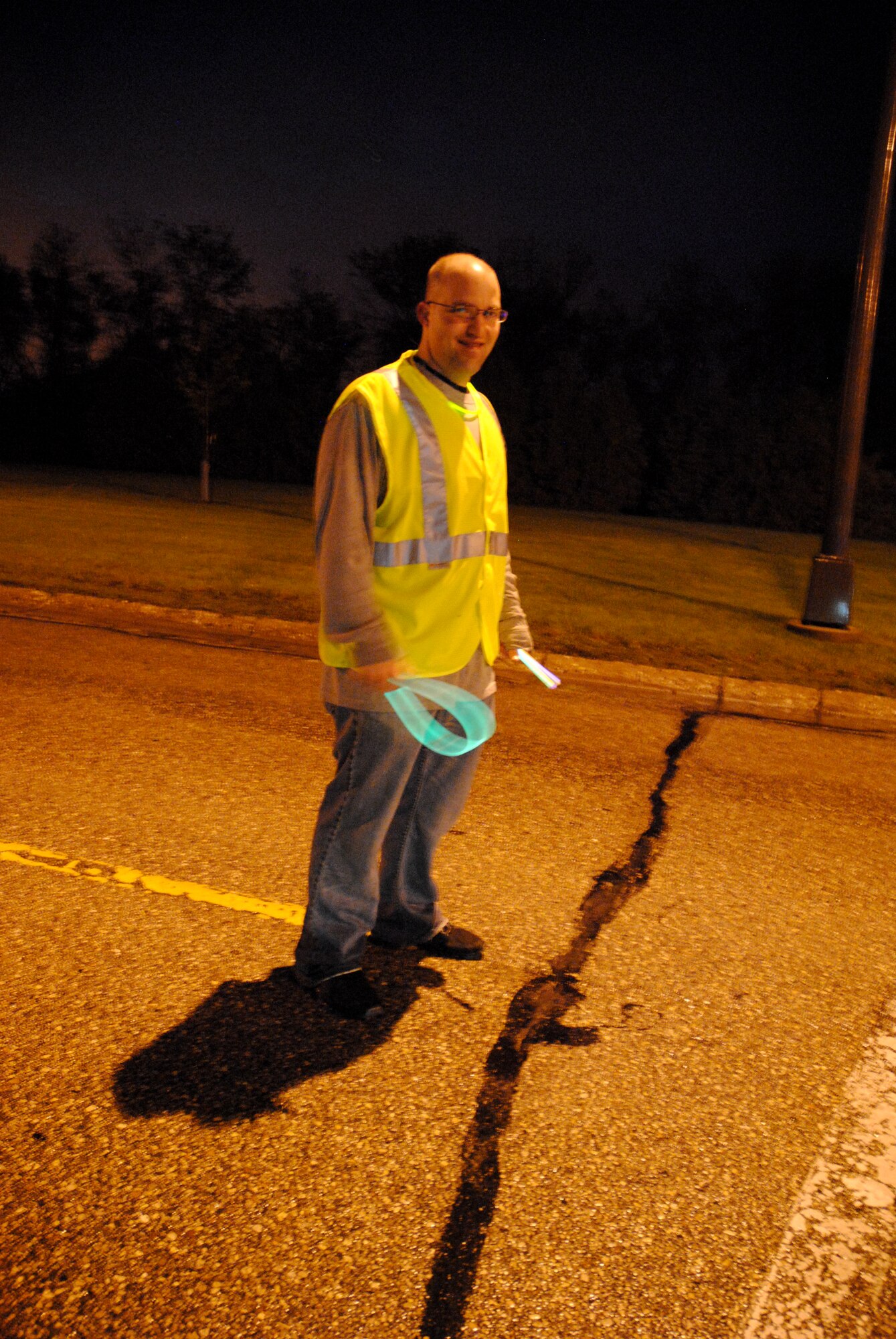 Staff Sgt. Clinton Biddix waves another group of competitors to the next part of the designated path during the 5K Glow Run sponsored by the Air Force Sergeants Association, Chapter 964 on May 30, 2014, on Grand Forks Air Force Base, N.D. Biddix was one of several Airmen who volunteered to serve as road guards and keep competitors safe during the event. (U.S. Air Force photo/Staff Sgt. Luis Loza Gutierrez) 