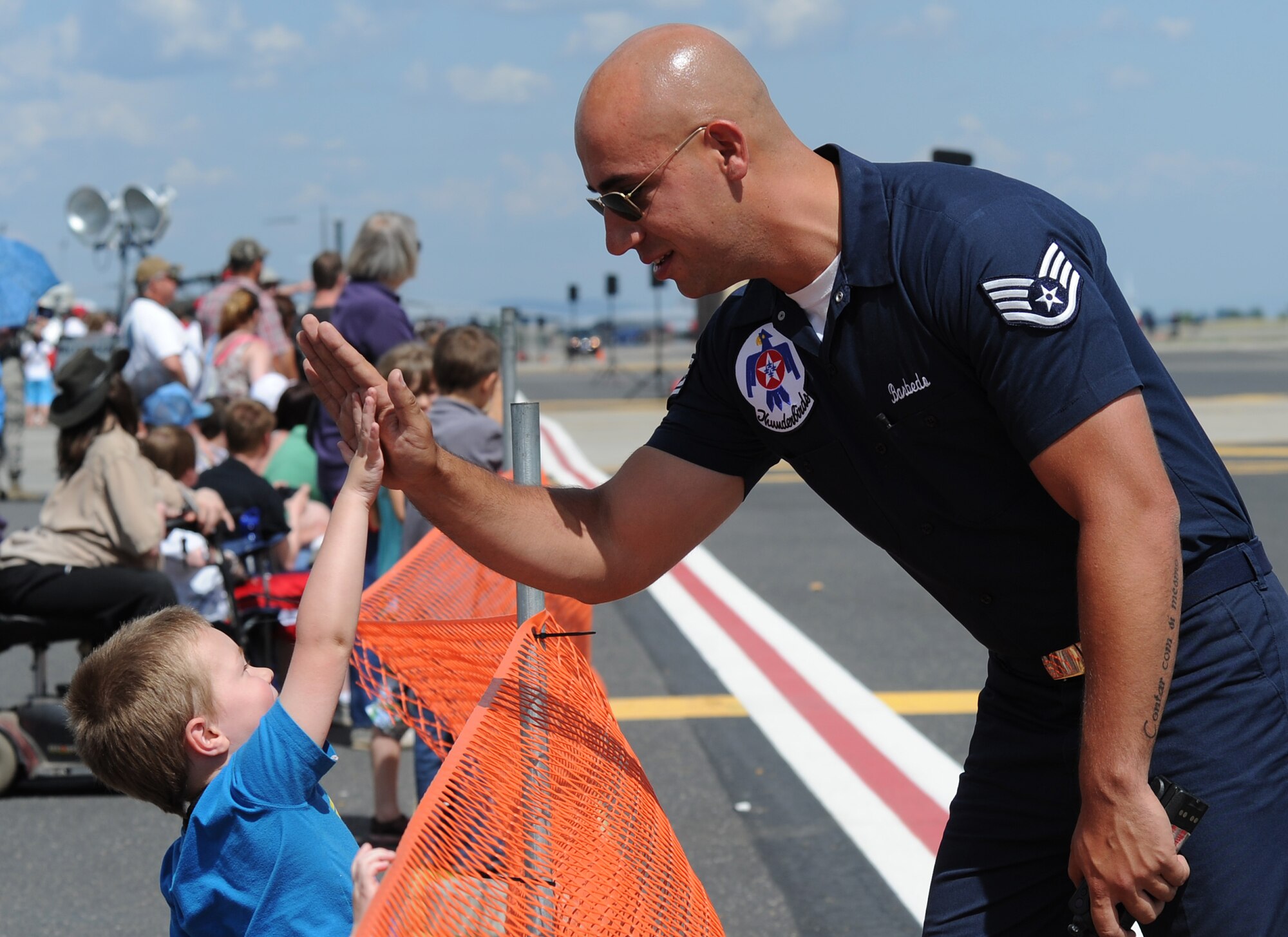 Staff Sgt. Tarkha Barbedo, a member of the Air Force Thunderbirds team, gives a child a high five during SkyFest 2014 at Fairchild Air Force Base, Wash., June 1, 2014. SkyFest is Fairchild’s air show and open house, giving the local and regional community the opportunity to view Airmen and our resources. The event typically draws more than 150,000 people. SkyFest 2008, headlined by the Blue Angels, was the largest event held in Spokane since the 1974 World’s Fair. (U.S. Air Force photo by Airman 1st Class Janelle Patiño/Released)