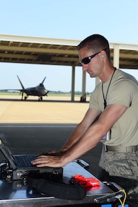 U.S. Air Force Staff Sgt. Justin Hubbard, 94th Fighter Squadron dedicated crew chief, refer to his computer during prior to the start of a training sortie at  Langley Air Force Base, Va., June 4, 2014. Hubbard was hand-selected as the dedicated crew chief out of 120 maintenance professionals for the Air Combat Command F-22 Demonstration Team.  (U.S. Air Force photo by Staff Sgt. Antoinette Gibson/Released)