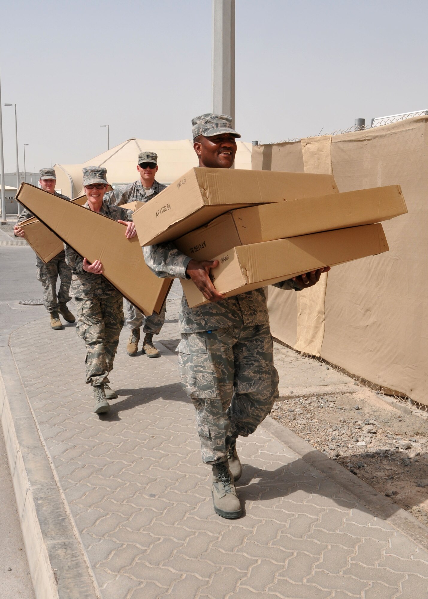 Air Force Master Sgt. Andre Williamson leads members of the chaplain’s and mental health offices as they carry new boxed guitars to the wing chapel June 4, 2014. The guitars were donated by a company in the United States to be used by Airmen assigned to the 380th Air Expeditionary Wing at the undisclosed location in Southwest Asia. (U.S. Air Force photo by Senior Master Sgt. Eric Peterson/Released)