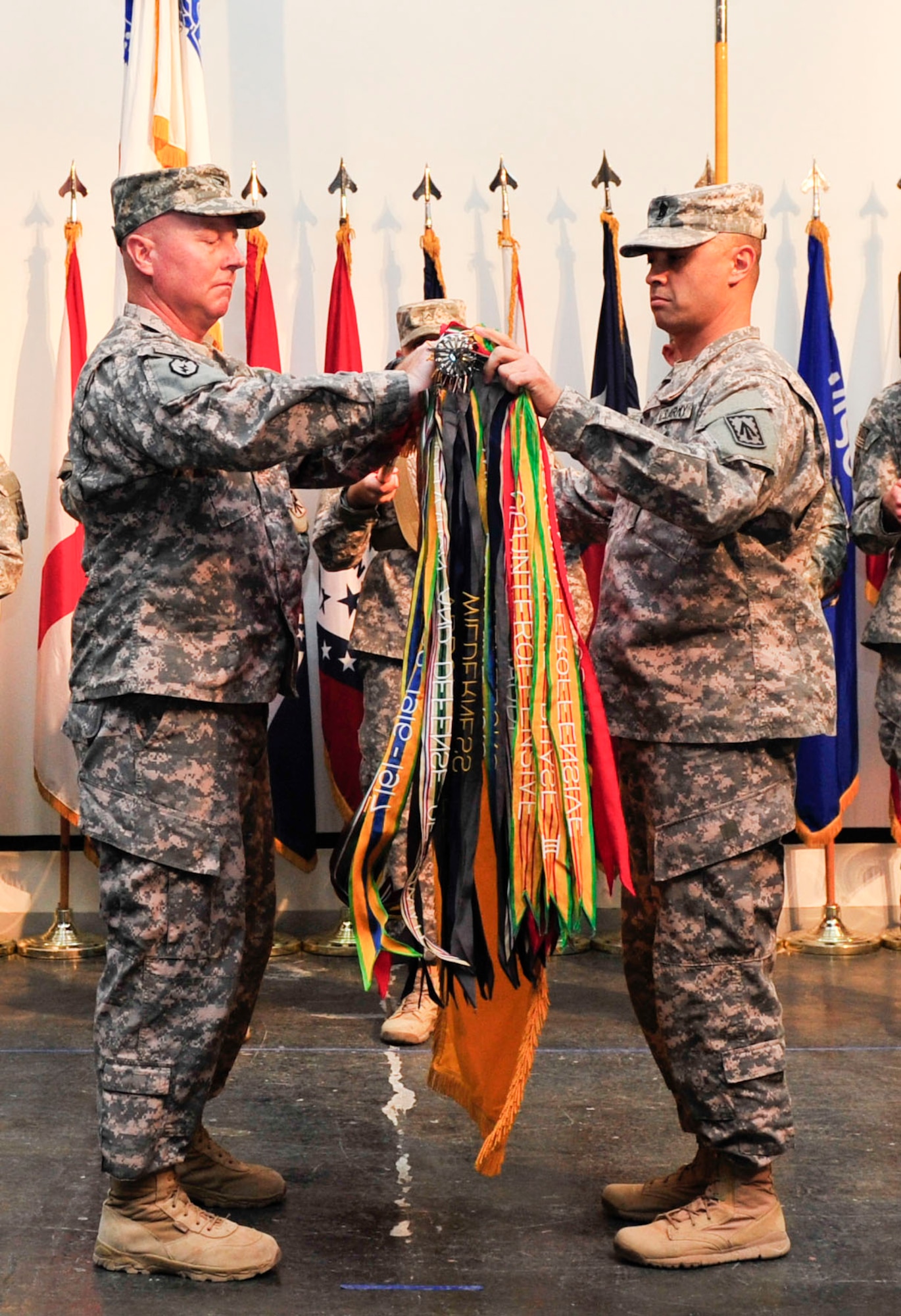 U.S. Army Col. Edward O’Neil, 108th Air Defense Artillery Brigade commander, and Command Sgt. Major John Foley, 108th Air Defense Artillery Brigade sergeant major, unfurl their brigade colors during a transfer of authority ceremony at Al Udeid Air Base, Qatar, May 30, 2014. The 108th ADA is replacing the 31st ADA as the command and control unit of air and missile defense forces in the U.S. Central Command area of responsibility. (U.S. Air Force photo by Senior Airman Colin Cates)