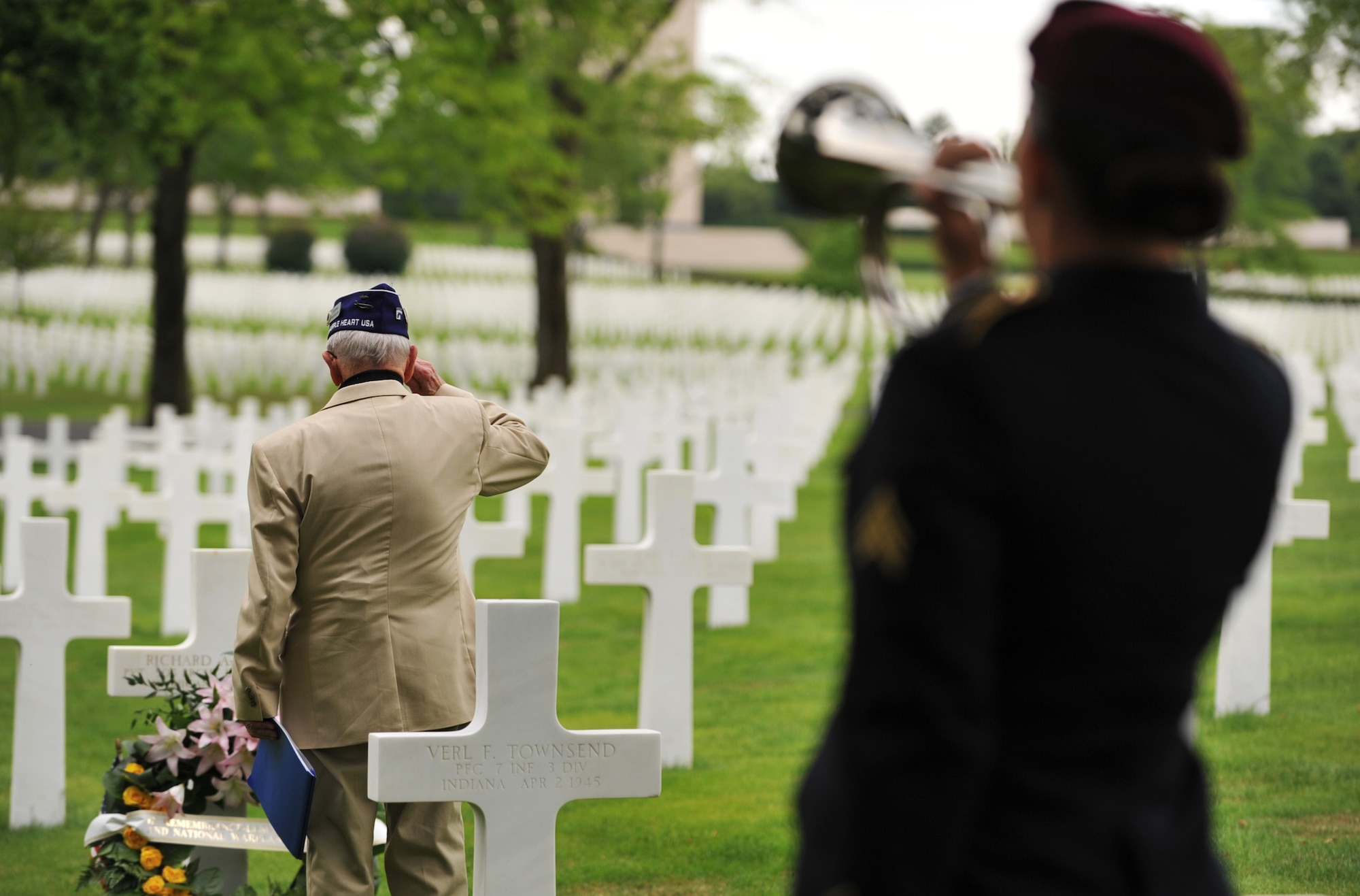 Leslie Cruise, a World War II veteran, salutes the grave of Pvt. Richard Vargas while Army Sgt. Jeannette Mason, 5th Quartermaster Theater Aerial Delivery Company parachute rigger, plays taps during a wreath laying ceremony at Lorraine American National Cemetery and Memorial, St. Avold, France, June 2, 2014. Seventy years ago on June 7, 1944 Pvt. Richard Vargas saved Cruise’s life during the invasion of Normandy. Cruise went to France several times prior to this visit looking for his friend’s grave in order to say thank you. (U.S. Air Force photo/Senior Airman Hailey Haux)