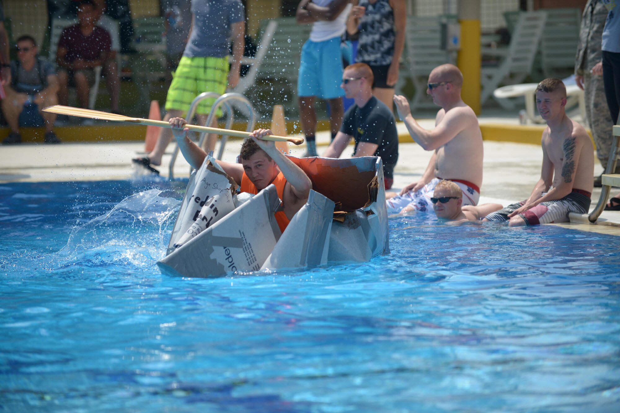 Senior Airman Michael Feagin, 39th Maintenance Squadron aerospace ground equipment journeyman, sinks in a cardboard boat May 29, 2014, Incirlik Air Base, Turkey. Teams constructed boats made of cardboard and duct tape to race each other to the end of the pool and back. (U.S. Air Force photo by Senior Airman Nicole Sikorski/Released)