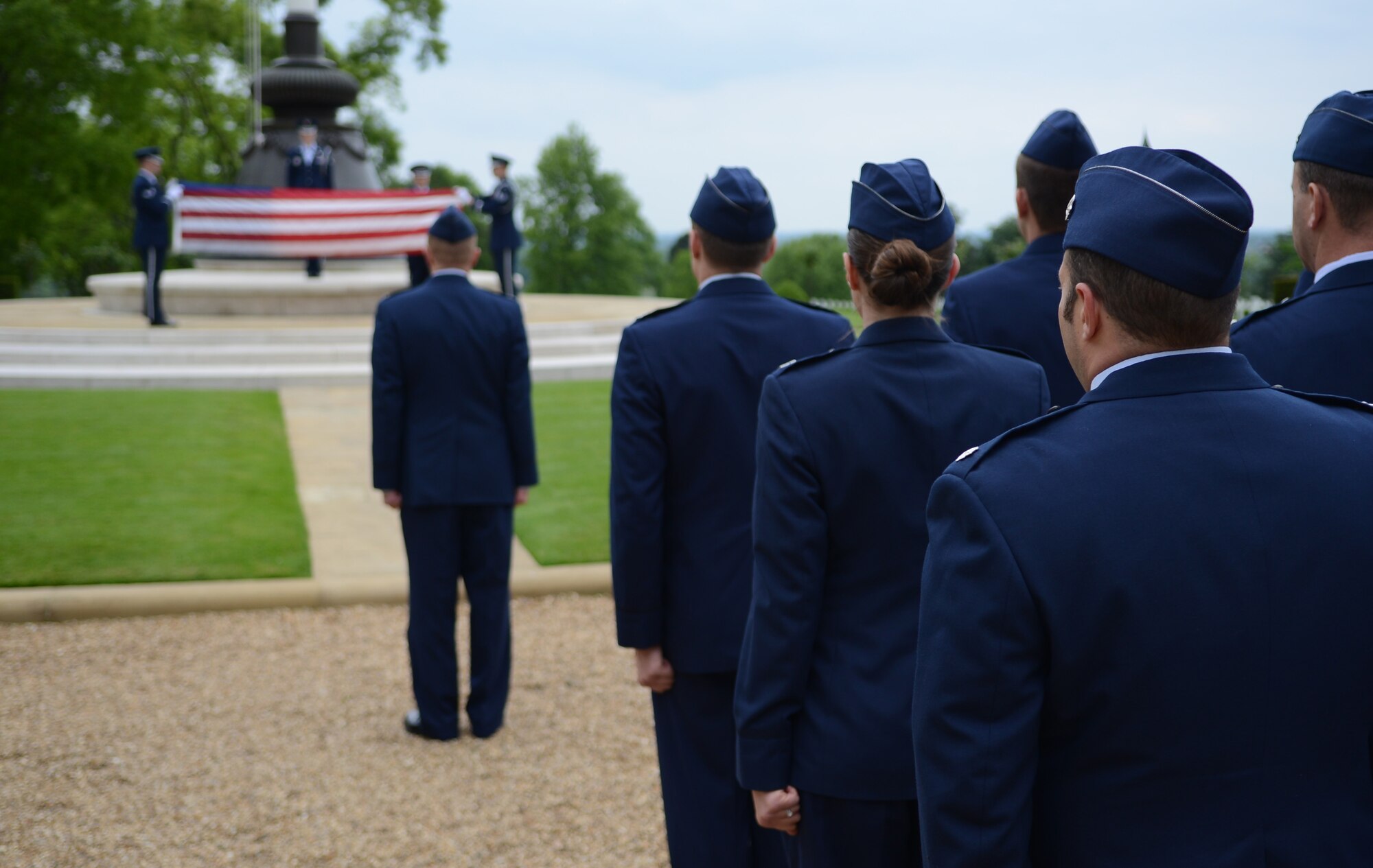 Members of the 7th Special Operations Squadron stand at attention as Team Mildenhall Honor Guard members fold the U.S. flag May 30, 2014, during a retreat ceremony at the Madingley American Cemetery in Cambridge, England. The 7th SOS held the ceremony as part of a 50th anniversary celebration for the squadron. (U.S. Air Force photo/Airman 1st Class Dillon Johnston/Released)