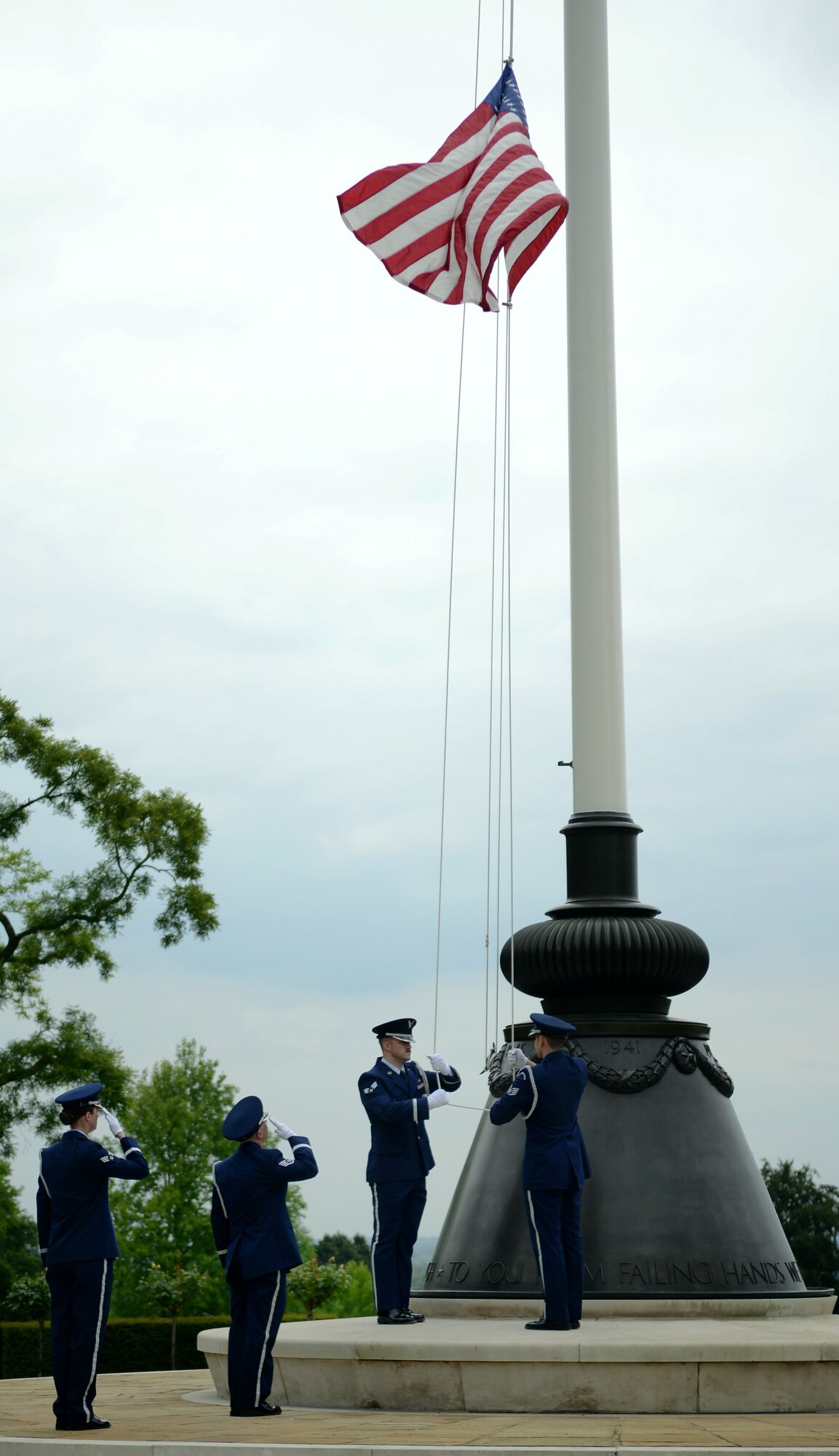 Team Mildenhall Honor Guard members lower the U.S. flag May 30, 2014, during a retreat ceremony at the Madingley American Cemetery in Cambridge, England. The retreat ceremony was part of the 50th anniversary celebration for the 7th Special Operations Squadron. (U.S. Air Force photo/Airman 1st Class Dillon Johnston/Released)