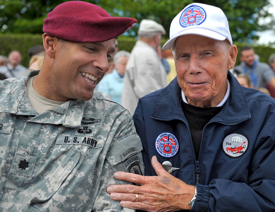 U.S. Army Lt. Col. Patrick S. Wilkins, left, talks with Dick Yates during a ceremony honoring the service of U.S. Army nurses during World War II, in Bolleville, Normandy, France, June 4, 2014. Wilkins is commander of the 1st Battalion, 503rd Infantry Regiment, 173rd Infantry Brigade Combat Team, and Yates is a delegate from the Washington, D.C., chapter of the 82nd Airborne Division Association.