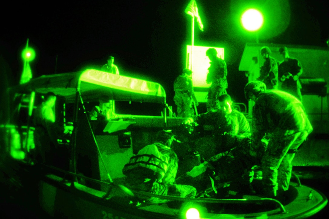 As seen through a night-vision device, the U.S. Coast Guard Maritime Safety and Security Team San Diego and the U.S. Marine Corps Security Forces Company simulate the egress of injured people onto a Coast Guard fast boat during an evacuation exercise in Guantanamo Bay, Cuba, Dec. 30, 2011.  
