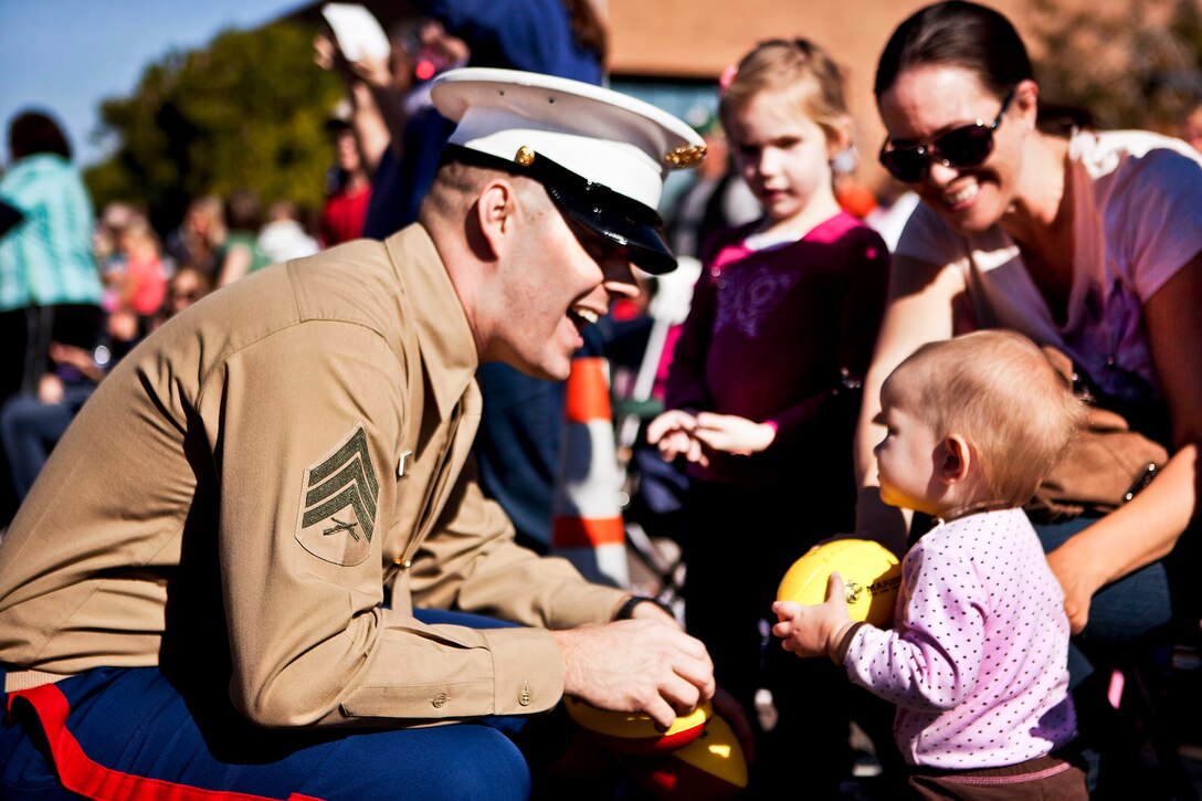 A Marine gives a football to a baby during the Fiesta Bowl Parade in Phoenix, Dec. 31, 2011. Marines walked in the parade, handing out footballs and information about the Semper Fidelis All-American Bowl, which features the nation’s top 100 senior football players.  
