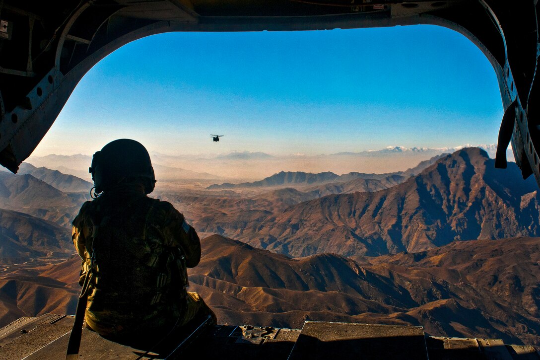 U.S. Army Spc. Devon Boxa admires the Afghan landscape out the back door of her CH-47D Chinook helicopter as another Chinook follows over Nangarhar province, Afghanistan, Dec. 17, 2011. Boxa is a crew chief assigned to Company B, 7th Battalion, 158th Aviation Regiment. The helicopters were flying from Kabul to Jalalabad.  
