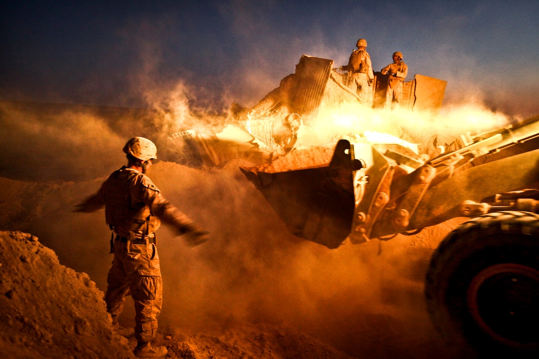 U.S. Marine Corps Sgt. Cody Palfreyman guides a bulldozer as it moves the berm surrounding a guard post on Firebase Saenz in Afghanistan's Helmand province, Dec. 14, 2011. Palfreyman is a combat engineer assigned to Alpha Company, 9th Engineer Support Battalion. The firebase is the first of several patrol bases being demilitarized by the Marines in December.  
