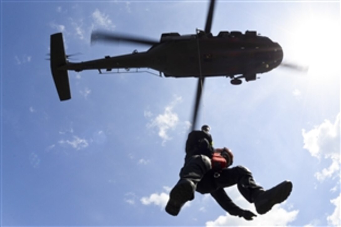 A member of a helicopter aquatic rescue team descends from a UH-60 Black Hawk helicopter to a rescue tower at Pawleys Island, S.C., June 3, 2014. South Carolina National Guardsmen are working with the state's emergency management division and local emergency agencies to effectively respond to hurricanes that may threaten the state.