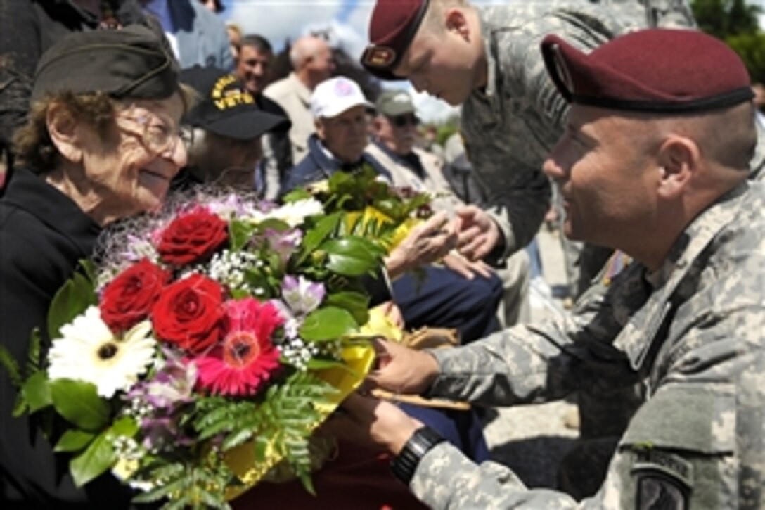 A U.S. paratrooper presents flowers to Ellan Levitsky-Orkin served as a U.S. Army nurse in Normandy during World War II, at a ceremony honoring the service of U.S. Army nurses during World War II, in Bolleville, France, June 4, 2014. 