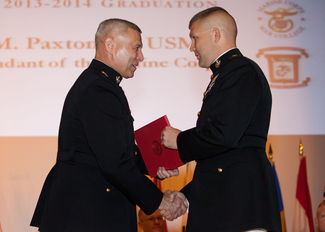 The Assistant Commandant of the Marine Corps, Gen. John M. Paxton, Jr., left, hands a diploma to a student who graduated from the Marine Corps University for the academic year of 2013-2014 at U.S. Marine Corps Base Quantico, Va., June 4, 2014. (U.S. Marine Corps by Cpl. Tia Dufour/Released)