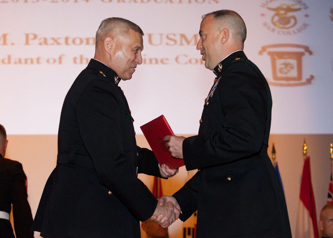 The Assistant Commandant of the Marine Corps, Gen. John M. Paxton, Jr., left, hands a diploma to a student who graduated from the Marine Corps University for the academic year of 2013-2014 at U.S. Marine Corps Base Quantico, Va., June 4, 2014. (U.S. Marine Corps by Cpl. Tia Dufour/Released)