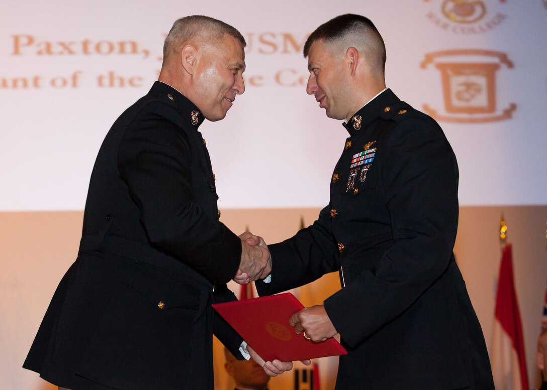 The Assistant Commandant of the Marine Corps, Gen. John M. Paxton, Jr., left, hands a diploma to a student who graduated from the Marine Corps University for the academic year of 2013-2014 at U.S. Marine Corps Base Quantico, Va., June 4, 2014. (U.S. Marine Corps by Cpl. Tia Dufour/Released)