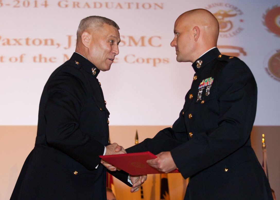 The Assistant Commandant of the Marine Corps, Gen. John M. Paxton, Jr., left, hands a diploma to a student who graduated from the Marine Corps University for the academic year of 2013-2014 at U.S. Marine Corps Base Quantico, Va., June 4, 2014. (U.S. Marine Corps by Cpl. Tia Dufour/Released)