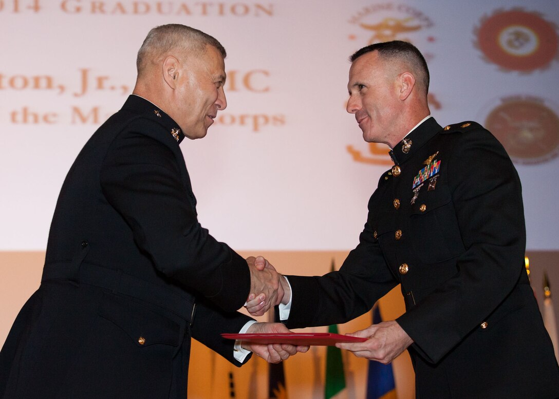 The Assistant Commandant of the Marine Corps, Gen. John M. Paxton, Jr., left, hands a diploma to a student who graduated from the Marine Corps University for the academic year of 2013-2014 at U.S. Marine Corps Base Quantico, Va., June 4, 2014. (U.S. Marine Corps by Cpl. Tia Dufour/Released)