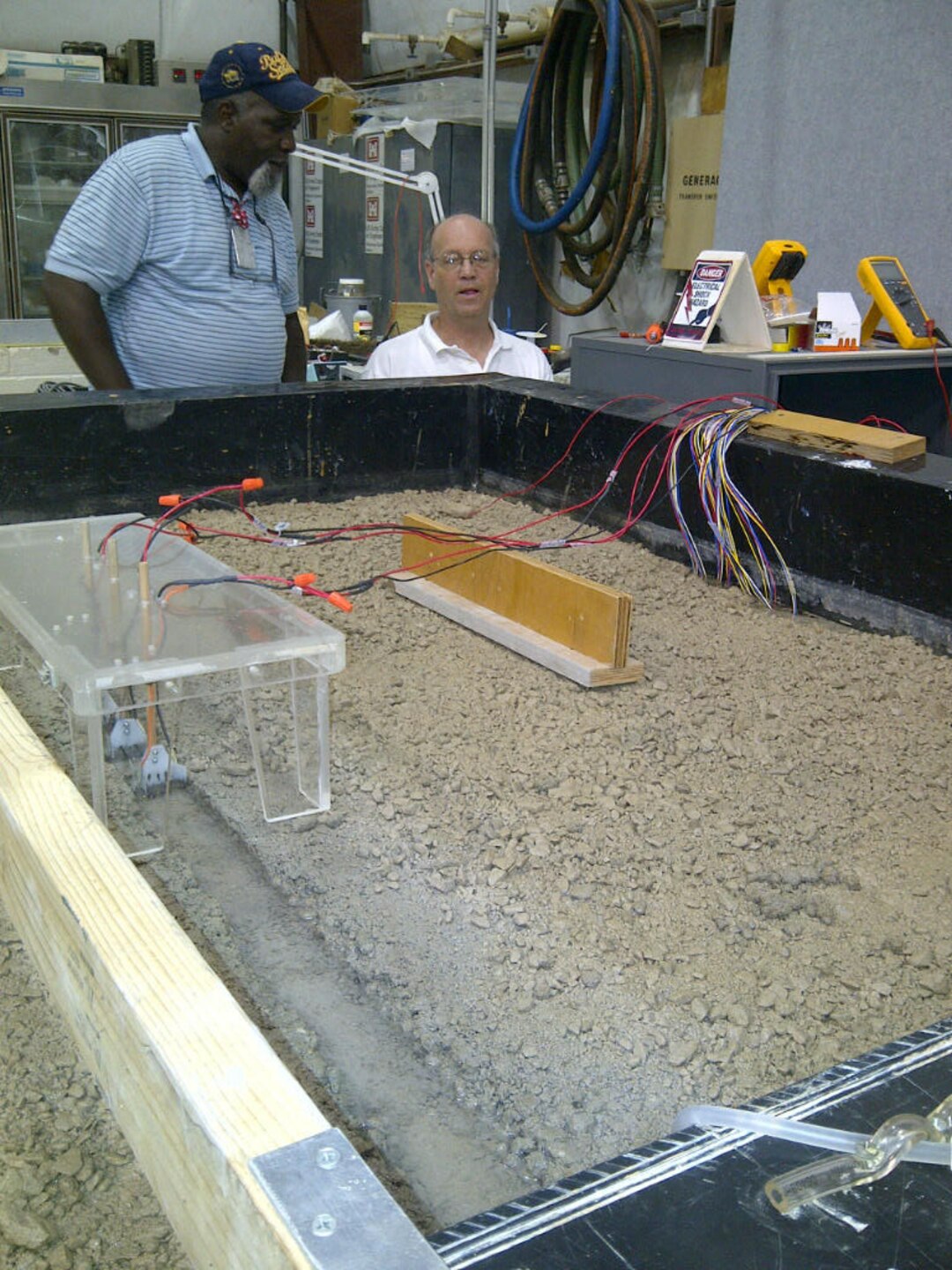 Mr. Richard Hudson, left, and Dr. David Gent, right, discuss the 1:1000 scale model of the Chicago Canal system in the HWRC "pit" area that is used to observe the potential corrosion-related effects of the electrical fish barriers in the canal and evaluate a mitigation approach for use in the canal.