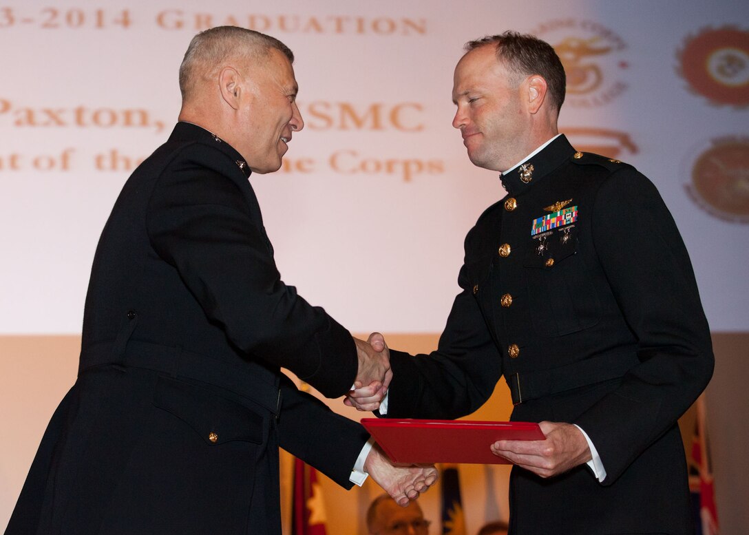 The Assistant Commandant of the Marine Corps, Gen. John M. Paxton, Jr., left, hands a diploma to a student who graduated from the Marine Corps University for the academic year of 2013-2014 at U.S. Marine Corps Base Quantico, Va., June 4, 2014. (U.S. Marine Corps by Cpl. Tia Dufour/Released)