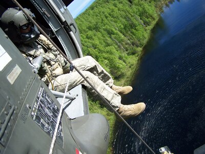 Army Sgt. Kevan J. Katkus, a crew chief with C Company, 1st Battalion, 207th Aviation Regiment, monitors a water bucket under the UH-60 Black hawk helicopter he is in to ensure it is lifted completely out of the water before the helicopter moves forward during training on wildfire response at Joint Base Elmendorf-Richardson. The unit conducted fire training June 9-10 to qualify new pilots and crew members, while re-certifying existing pilots and crew for emergency wildfire missions.