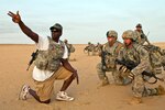 Staff Sgt. Calvin James, left, with 4th Battalion, 118th Infantry Regiment, talks with Soldiers from the battalion's Company C while he roleplays as an embassy liaison in during an embassy defense and evacuation exercise at Range 5 near Camp Buehring, Kuwait.