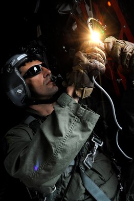 Tech. Sgt. Andy Strause signals to nearby aircraft May 7, 2014, while on a joint refueling training mission out of Kadena Air Base, Japan. During the mission, the MC-130P Combat Shadow crew from the 17th Special Operations Squadron refueled two helicopters and performed essential pilot training. (U.S. Air Force photo/Senior Airman Maeson L. Elleman)