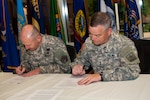 Army Maj. Gen. Judd H. Lyons, right, acting director Army National Guard, and Army Lt. Gen. Edward C. Cardon, commander U.S. Army Cyber Command, sign a memorandum of understanding during an event June 5, 2014, at Fort Belvoir, Virginia. The memorandum establishes a commitment to a total force solution in cyber space solutions and aligns the Army Guard's 1636th Cyber Protection Team under the command and control of ARCYBER. 