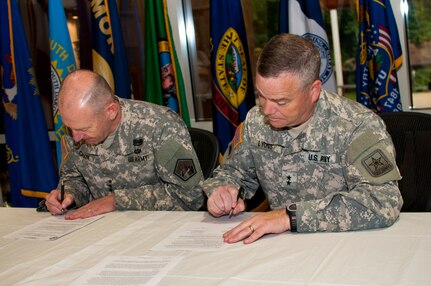 Army Maj. Gen. Judd H. Lyons, right, acting director Army National Guard, and Army Lt. Gen. Edward C. Cardon, commander U.S. Army Cyber Command, sign a memorandum of understanding during an event June 5, 2014, at Fort Belvoir, Virginia. The memorandum establishes a commitment to a total force solution in cyber space solutions and aligns the Army Guard's 1636th Cyber Protection Team under the command and control of ARCYBER. 