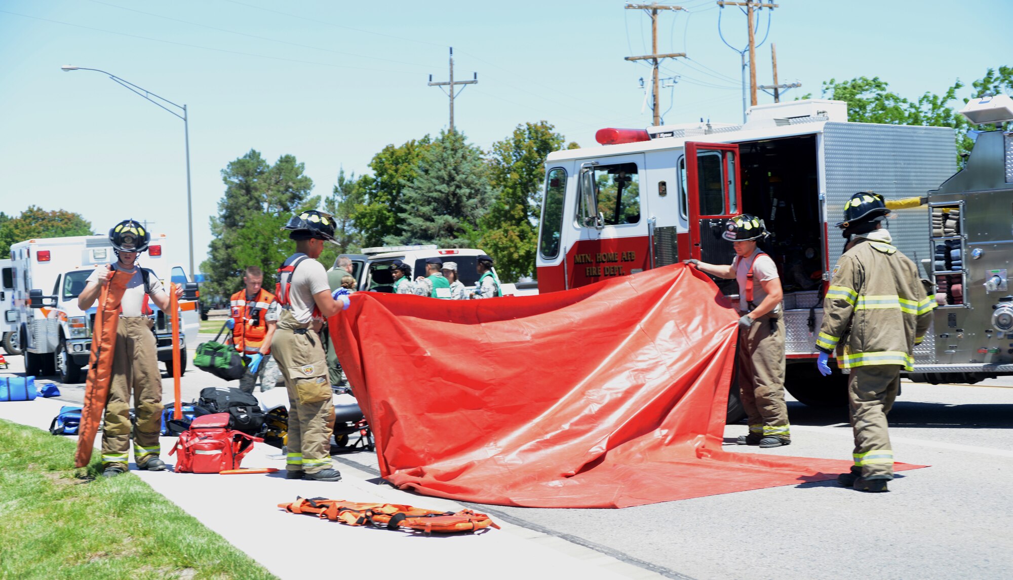 Firefighter from the 366th Civil Engineering Squadron fold up a red tarp used as an area for exercise "victims" to sit on during an accident simulation June 4, 2014, at Mountain Home Air Force Base, Idaho. Exercises occur periodically throughout the year in an effort to train Airmen. (U. S. Air Force photo by Senior Airman Benjamin Sutton/Released)