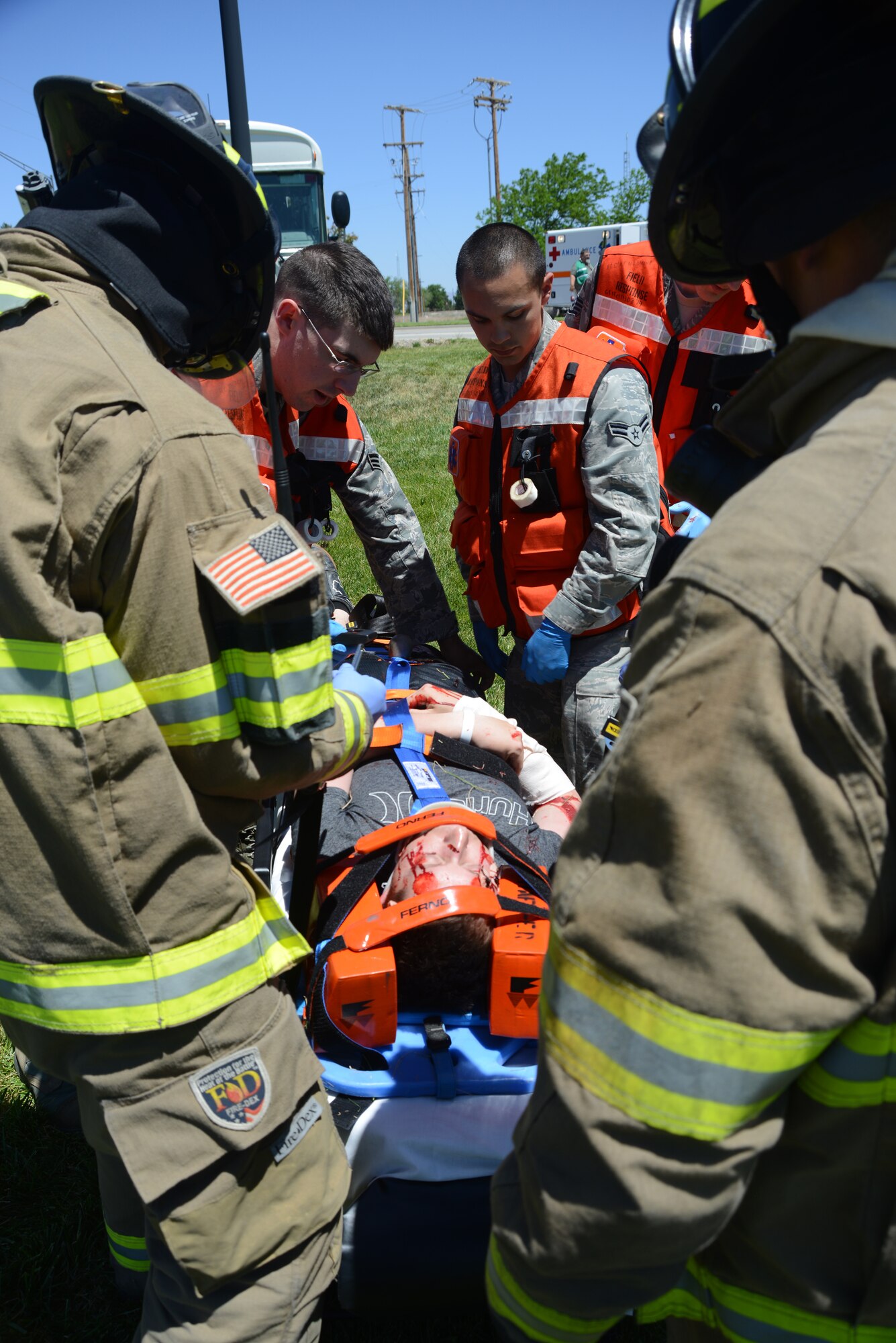 Multiple first-responders assist an exercise victim June 4, 2014, during a training scenario at Mountain Home Air Force Base, Idaho. Victims spent the morning being painted in moulage in order to have the appearance of cuts and bruises. (U. S. Air Force photo by Senior Airman Benjamin Sutton/Released)
